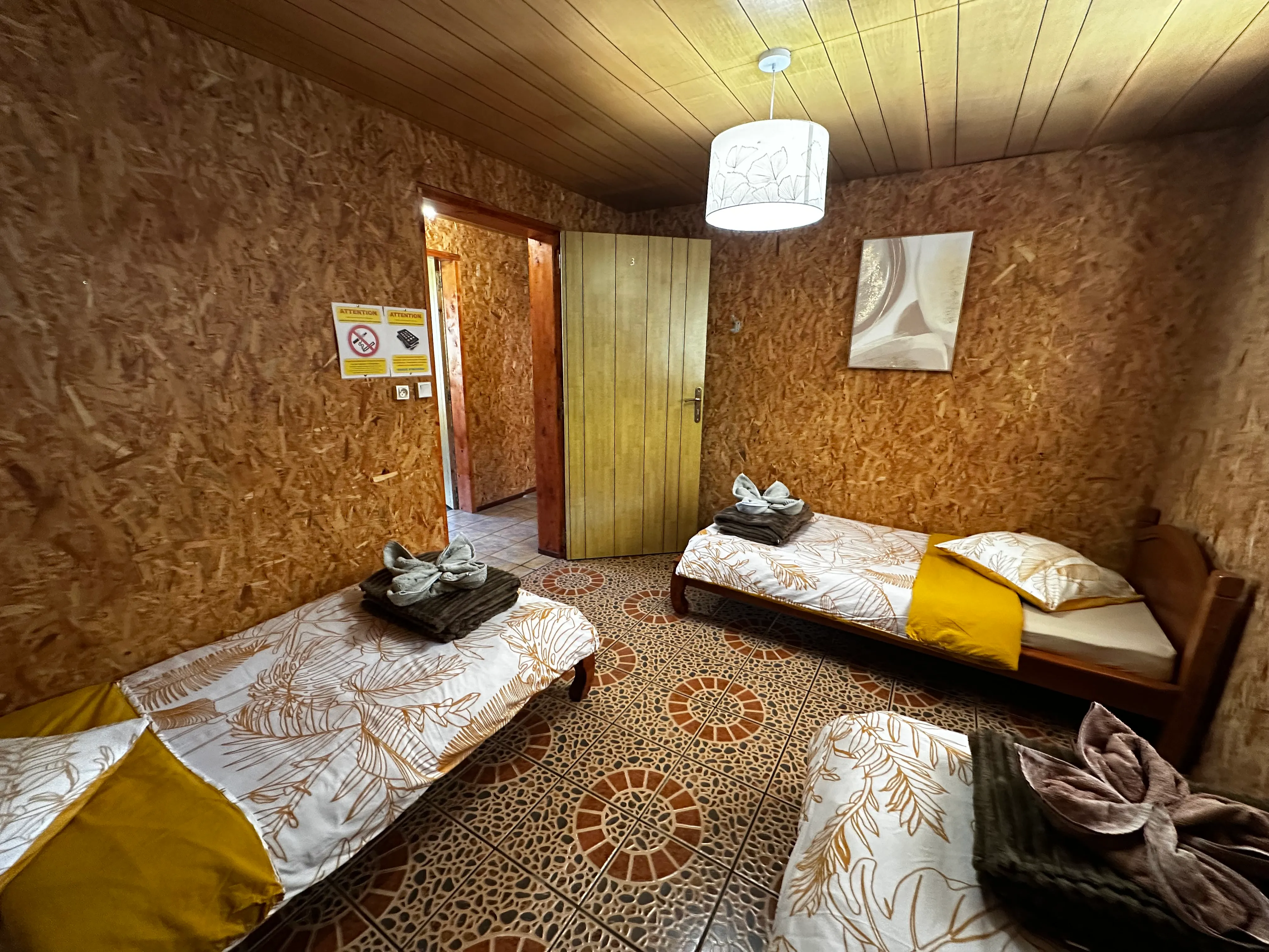 Dortoir 3 places : lits simples en bois sous les combles