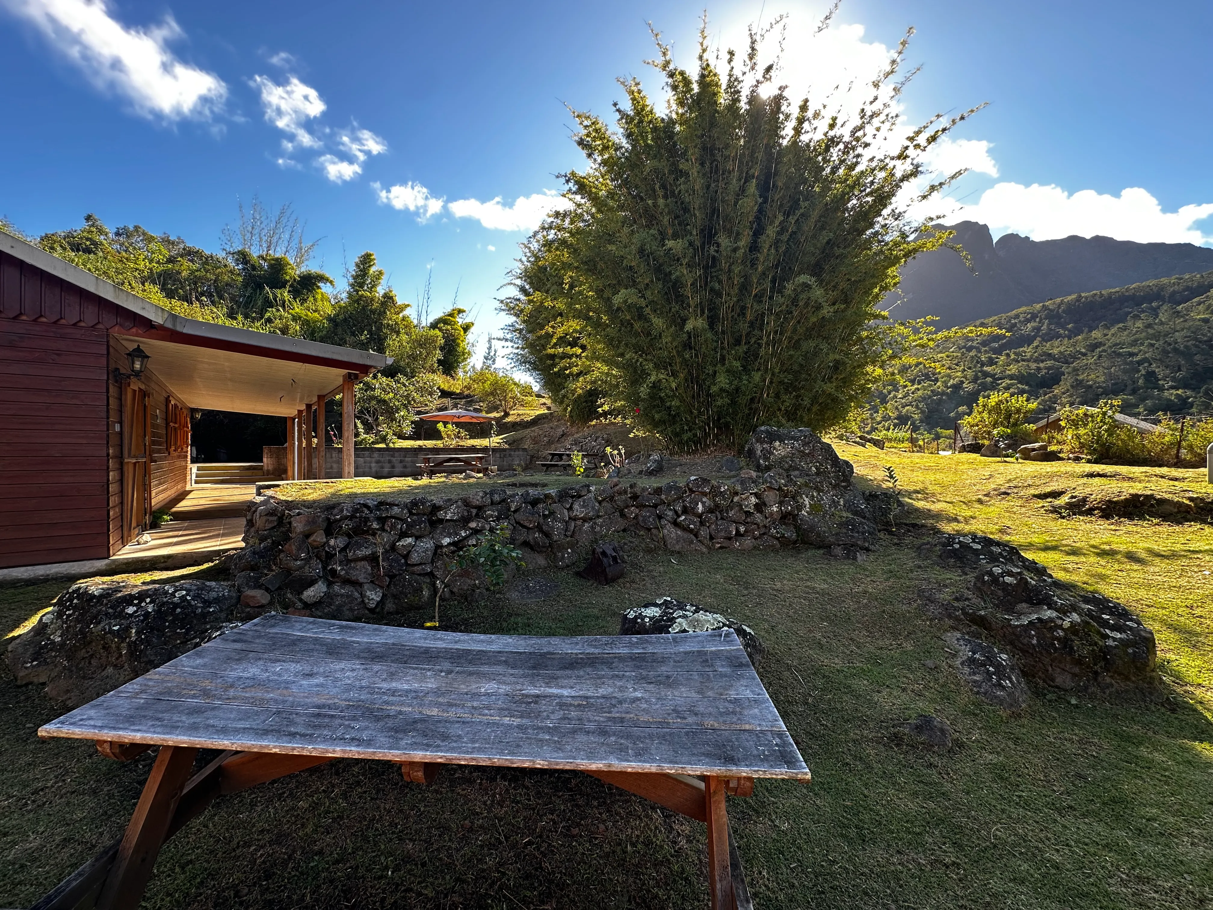 La terrasse couverte du gîte, son jardin en pierres sèches et les montagnes du cirque en arrière-plan