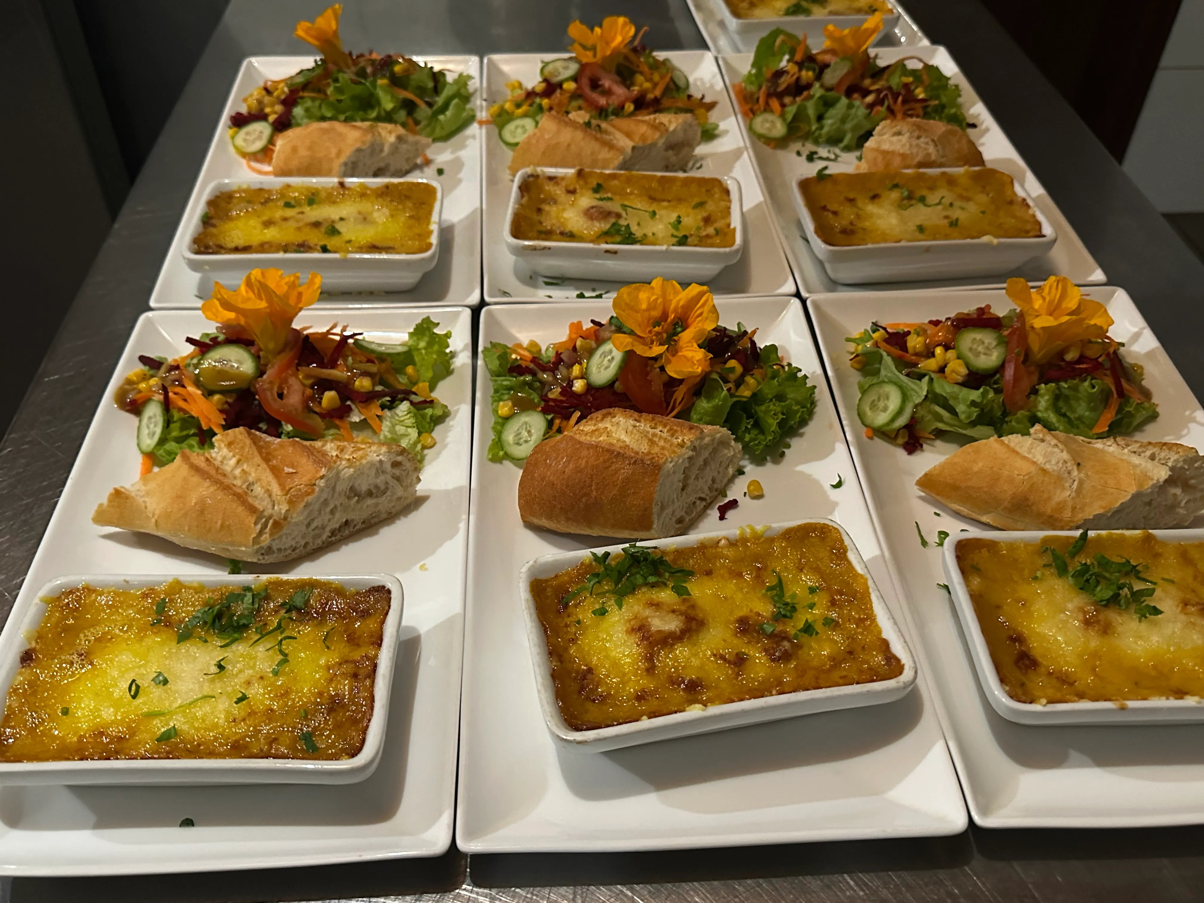 Assiettes de la table d'hôte : gratins dorés, salades fraîches et pain